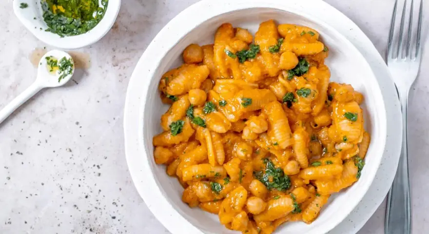 Herzhaftes Pasta e Ceci mit Kichererbsen in cremiger Sauce, garniert mit frischer Petersilie. Daneben eine kleine Schale mit Kräuteröl.