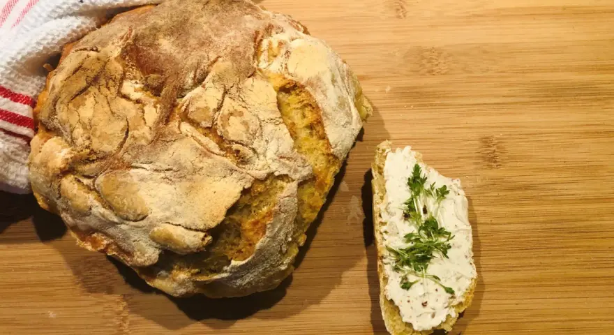 Ein rustikales, frisch gebackenes italienisches Brot Rezept, das genial einfach ist. Daneben ein Stück Brot mit Frischkäse und Kresse.