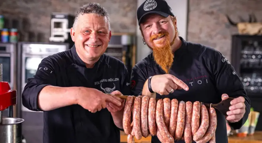 Zwei Metzger präsentieren stolz eine Reihe von frisch gefüllten Salsiccia mit Haut, bereit zum Braten.