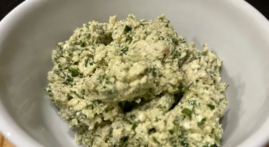 Ein cremiger Käseaufstrich mit Kräutern, wie er für ein Moretum Rezept typisch ist.