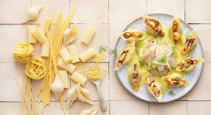Gefüllte Conchiglioni mit Meeresfrüchten, ein köstliches italienisches Rezept. Daneben verschiedene italienische Pasta-Sorten.