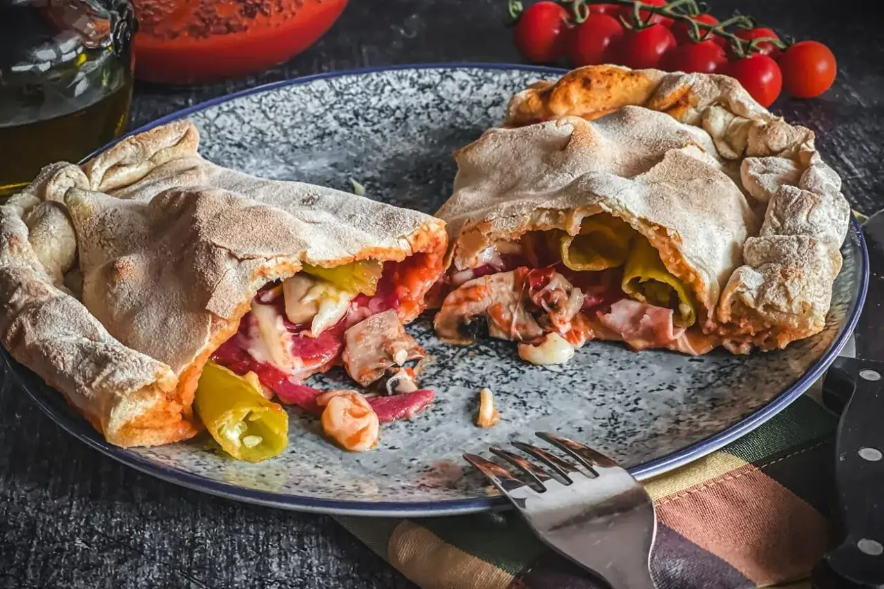 Ein aufgeschnittener, herzhafter pizza calzone mit Pilzen, Salami und K&auml;se, bereit zum Genie&szlig;en.