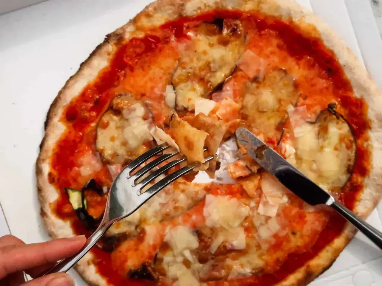 So wie essen Italiener Pizza: mit Messer und Gabel, um jeden Bissen der k&ouml;stlichen Melanzani-Pizza zu genie&szlig;en.