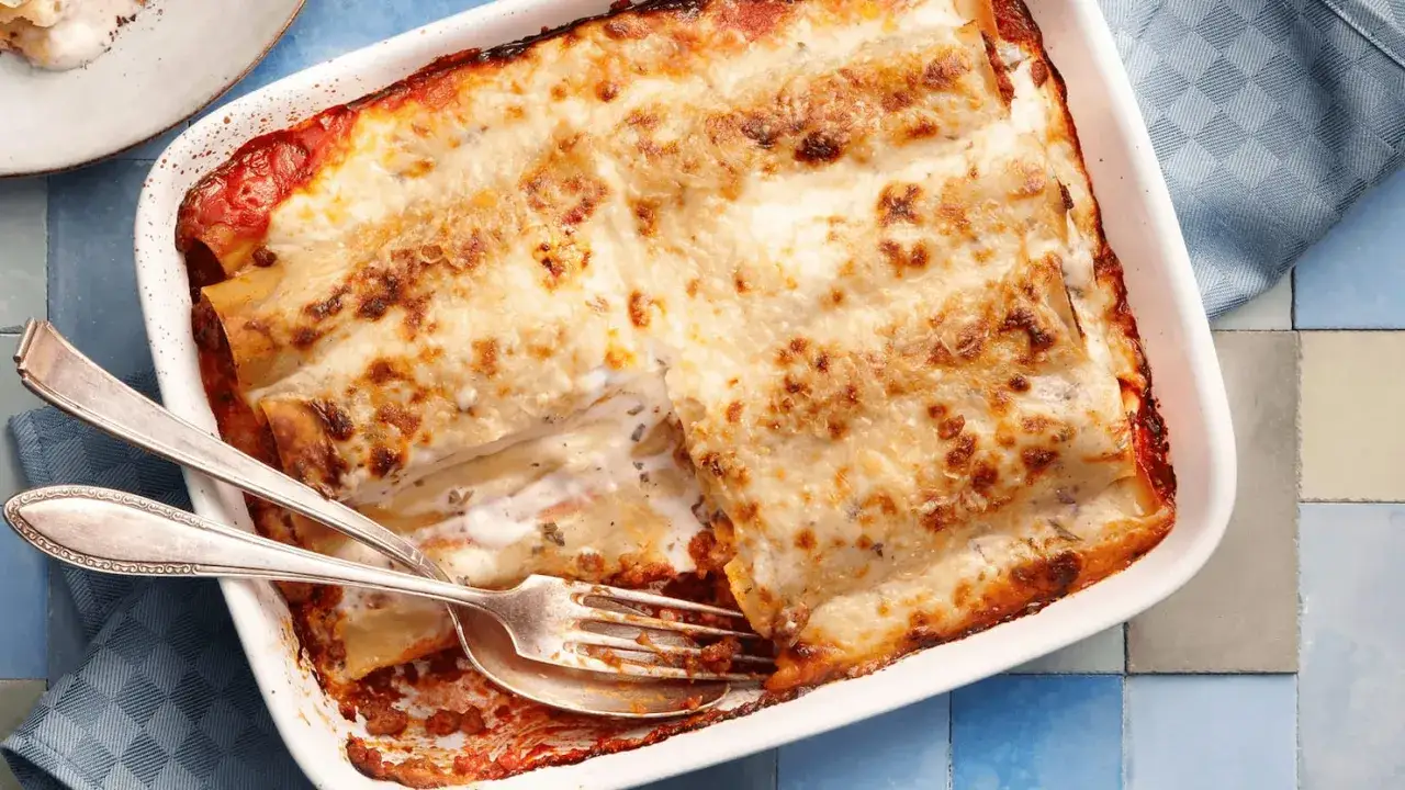 &Uuml;berbackene Cannelloni mit Hackfleischf&uuml;llung, goldbraun gebacken, mit einer Gabel zum Servieren.
