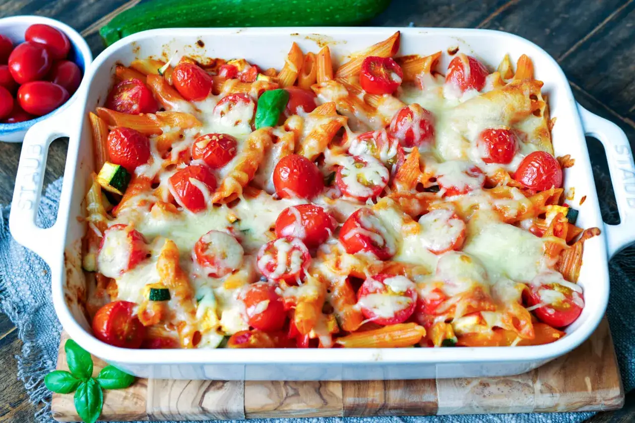 Ein k&ouml;stlicher, schneller Nudelauflauf mit Penne, Kirschtomaten und geschmolzenem K&auml;se, garniert mit frischem Basilikum.