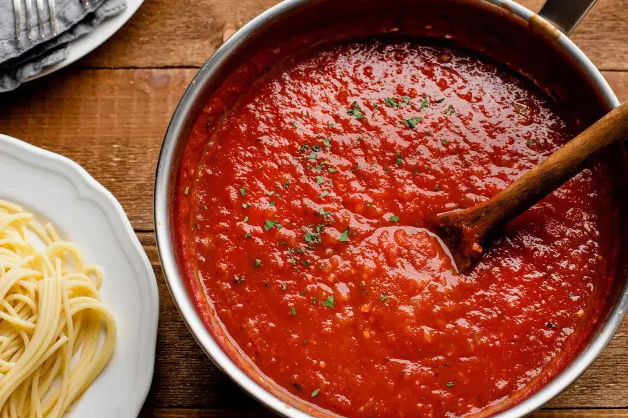 Ein Topf mit k&ouml;stlichem Sugo di Pomodoro, bereit, &uuml;ber frische Spaghetti gegossen zu werden. Ein Holzl&ouml;ffel r&uuml;hrt in der rubinroten Sauce.