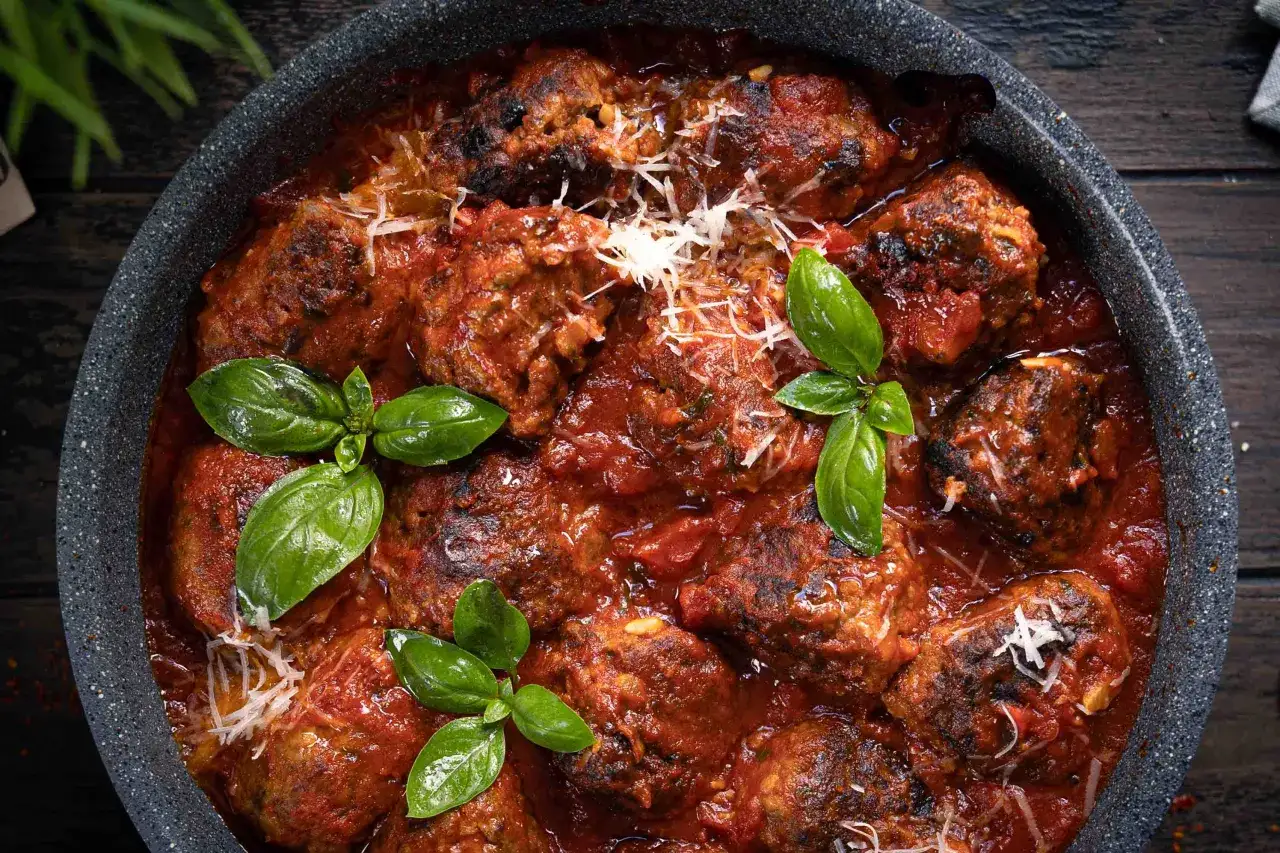 Herzhaftes involtini rezept im backofen, geschmort in Tomatensauce, garniert mit Parmesan und frischem Basilikum.