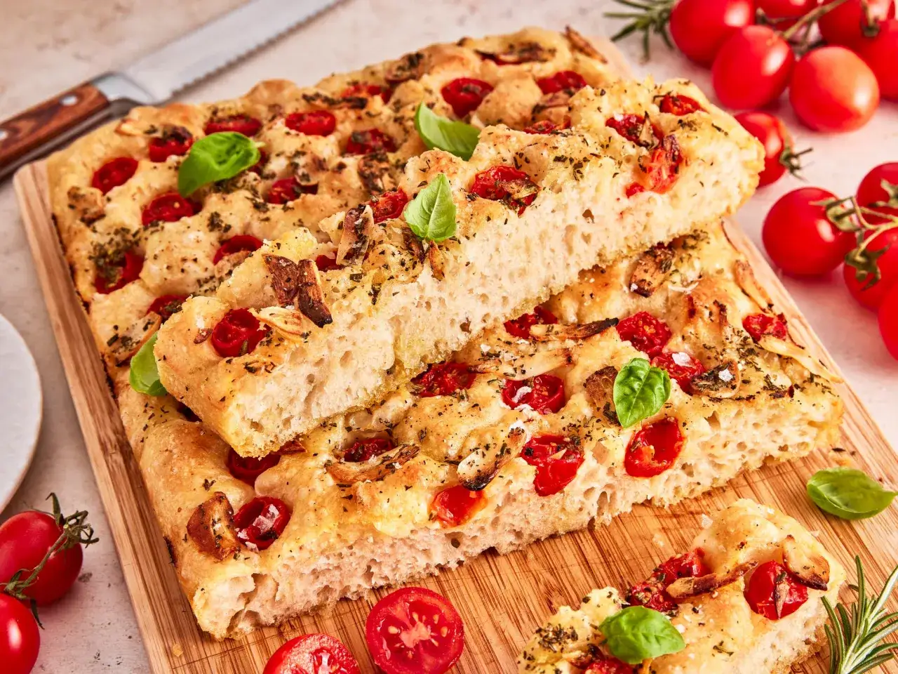 Saftige focaccia mit tomaten, garniert mit frischem Basilikum und Rosmarin. Perfekt f&uuml;r einen mediterranen Genuss.