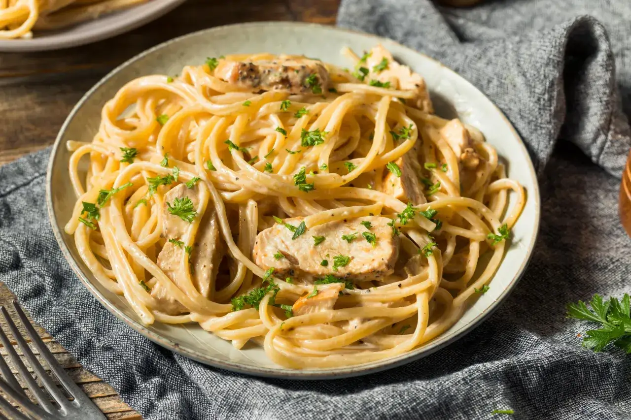 Cremiges Pasta Alfredo mit zarten H&auml;hnchenst&uuml;cken, garniert mit frischer Petersilie. Ein k&ouml;stliches Gericht, das zum Genie&szlig;en einl&auml;dt.