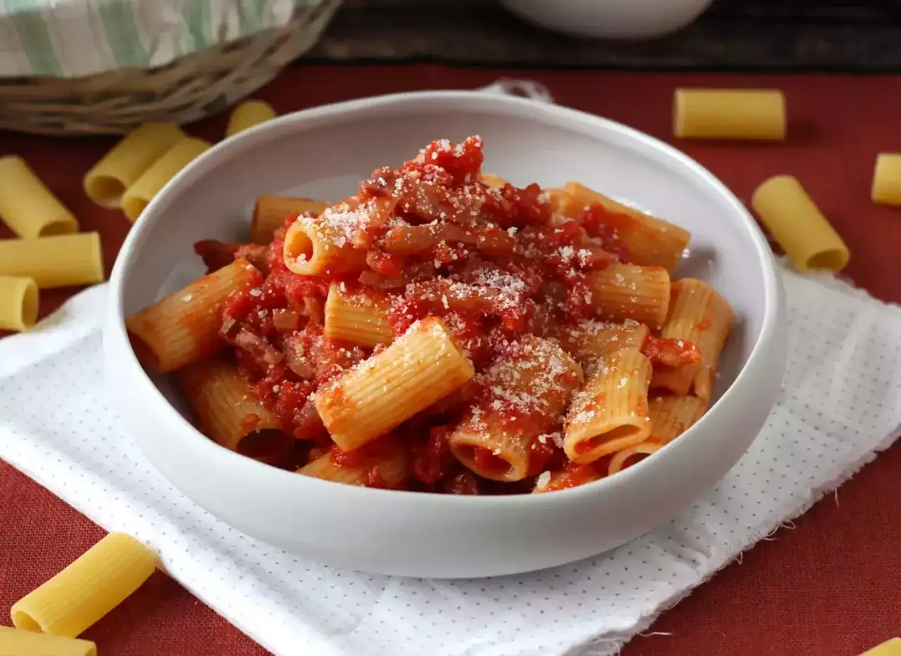Herzhaftes Rigatoni all'Amatriciana, ein klassisches italienisches amatriciana rezept, serviert in einer weißen Schüssel, bestreut mit Parmesan.