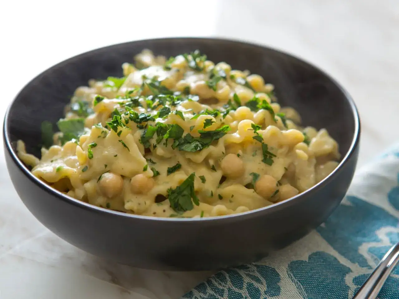 Dampfender Teller Pasta Ceci mit Kichererbsen und Petersilie, eine herzhafte Mahlzeit.
