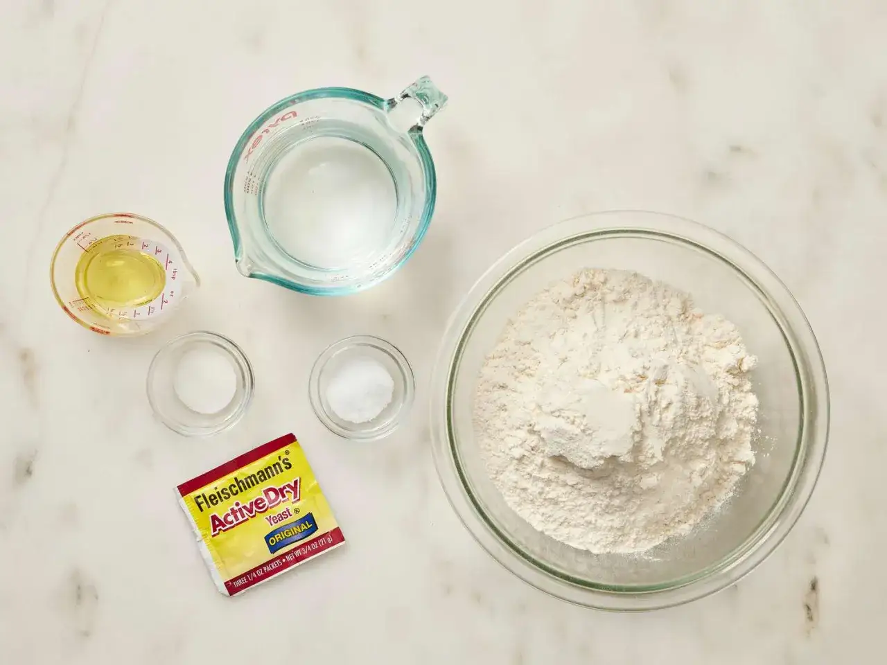 Zutaten f&uuml;r ein Pizzateig Rezept mit frischer Hefe: Mehl, Wasser, &Ouml;l, Salz und Hefe.