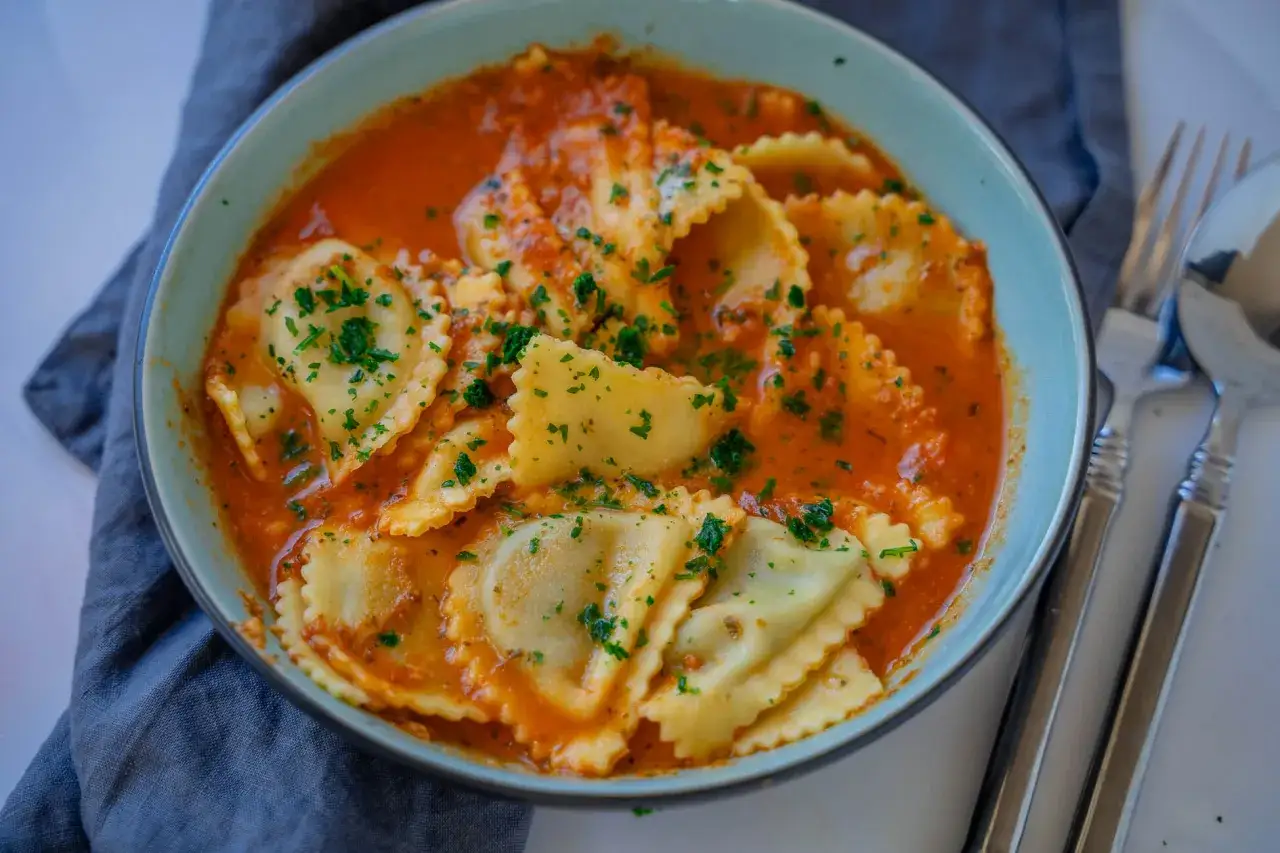 Ravioli in Tomatensauce, garniert mit Petersilie. Eine köstliche Antwort auf die Frage, welche Sauce zu Tortellini passt.