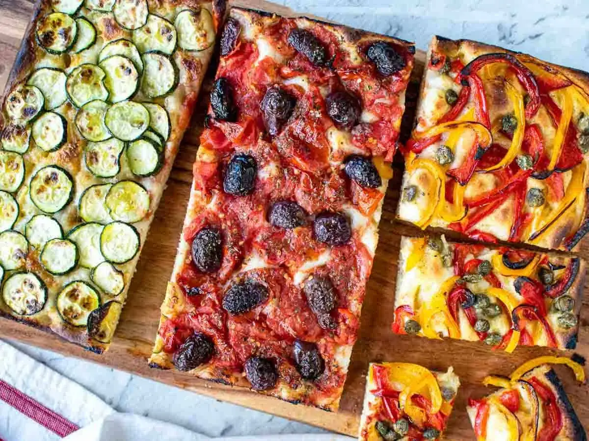 Verschiedene Focaccia-Varianten zum Belegen: mit Zucchini, Tomaten und Oliven, sowie mit Paprika und Kapern.