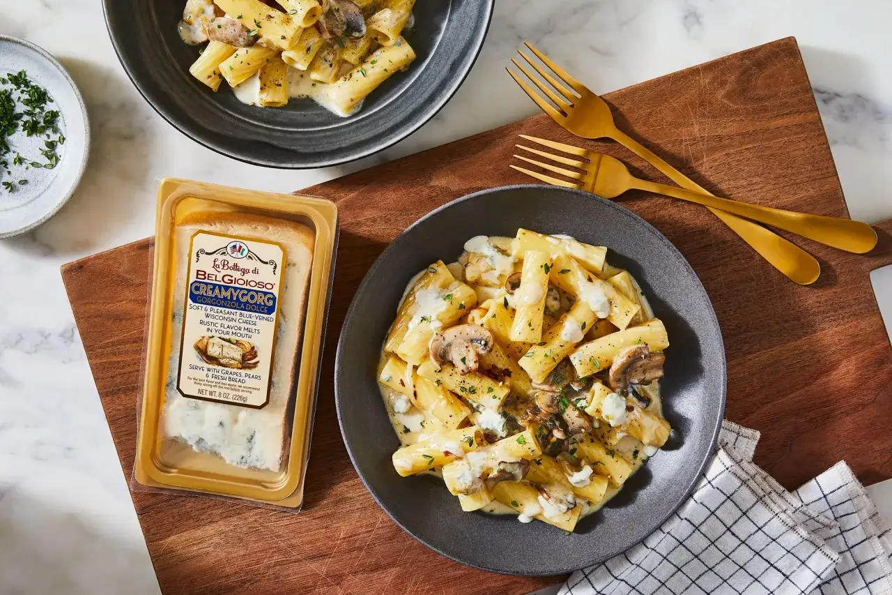 Pasta mit Pilzen und cremiger Gorgonzola-Sauce, daneben ein Laib Gorgonzola-K&auml;se.