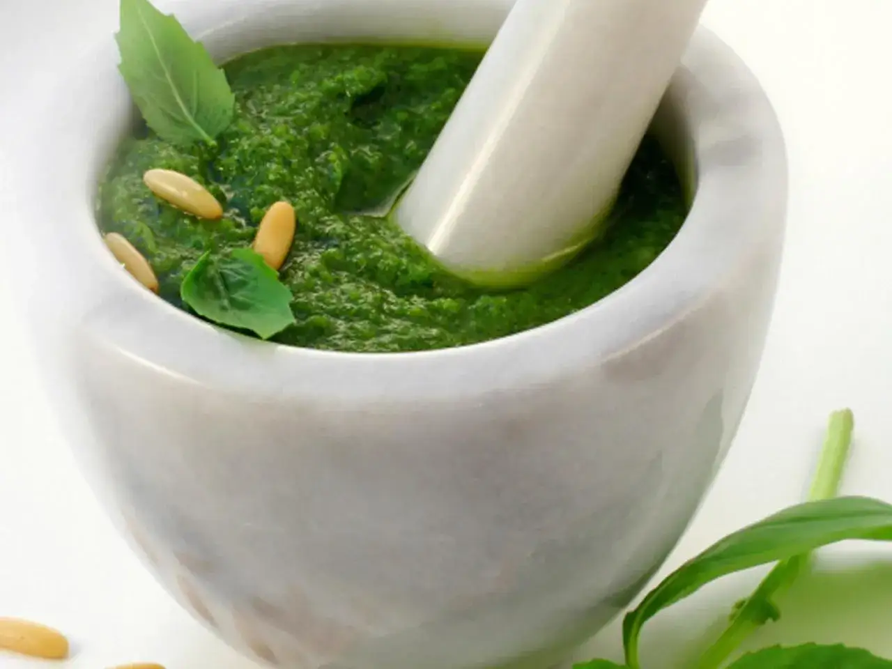 Frisches basilikum pesto in einem Marmorm&ouml;rser, garniert mit Pinienkernen und Basilikumbl&auml;ttern.