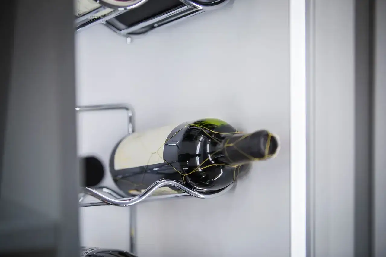 Offener Rotwein lagern: Eine Flasche Rotwein liegt auf einem Chrom-Gestell in einem K&uuml;hlschrank.