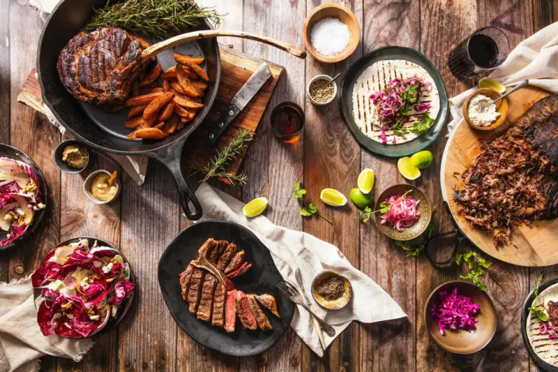 Ein Sommelier wählt den perfekten Wein zu saftigen Steaks, Beilagen und frischen Salaten.
