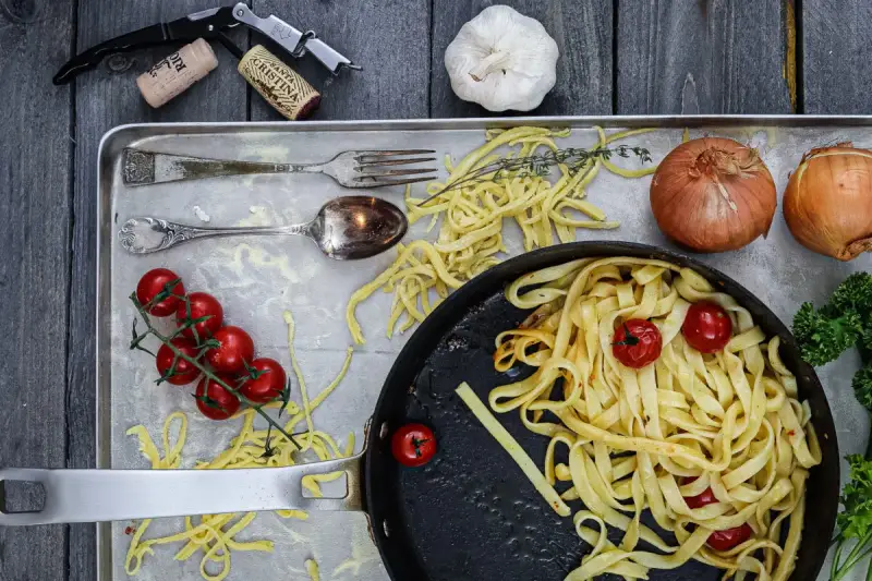 Frische Nudeln aus Hartweizengries, Tomaten, Zwiebeln und Knoblauch auf einem Blech. Ein Festmahl für Genießer!