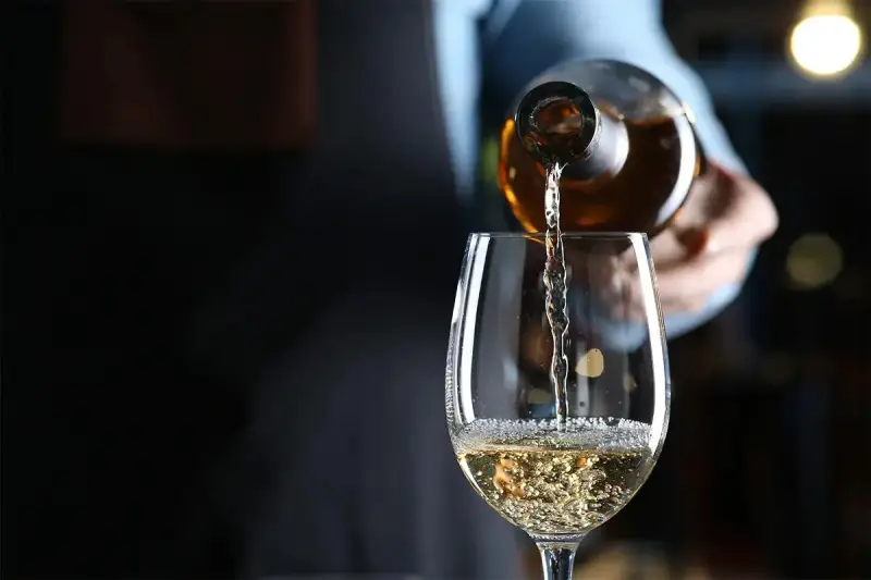 Weißwein wird in ein Glas gegossen. Die natürlichen wein zutaten sind im Glas sichtbar.
